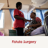 Two women talking to eachother, one is wearing the CBM logo shirt and one is sitting down on the bed with the captions'fistula surgery'